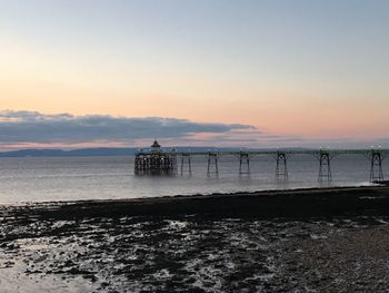 Pier in sea against sky during sunset