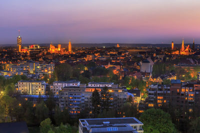 Illuminated cityscape against sky at sunset