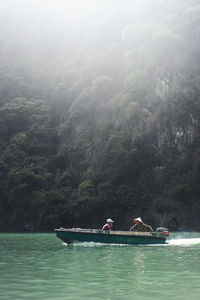 People on boat against mountain