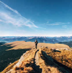 Full length rear view of man standing on mountain against sky