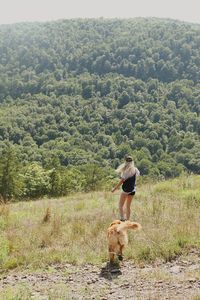 Full length of woman with dog on field