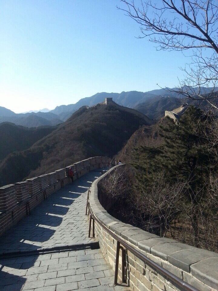 mountain, clear sky, the way forward, mountain range, tree, built structure, blue, tranquility, copy space, tranquil scene, railing, road, scenics, architecture, nature, beauty in nature, landscape, leading, sunlight, day