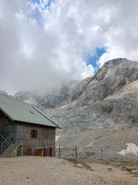 Built structure on land by mountain against sky