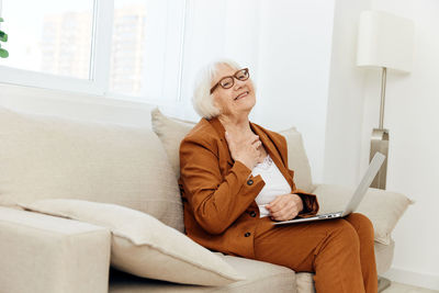 Young woman using laptop while sitting on sofa at home