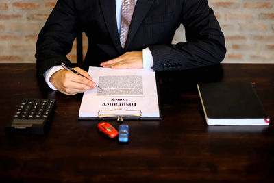 Midsection of man using mobile phone while sitting on table