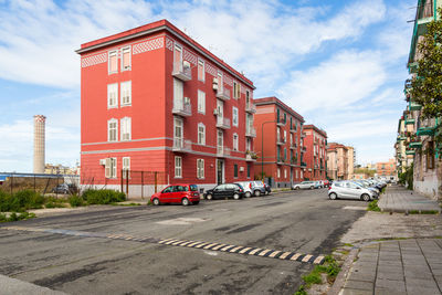 Cars on street by buildings in city against sky