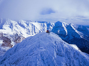 People on snowcapped mountain against sky during winter