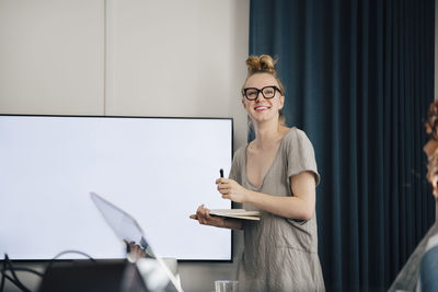 Smiling young genderblend entrepreneur giving presentation while looking away in board room during meeting