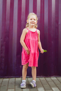 Portrait of young woman standing against wall