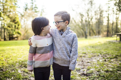 Cute brother and sister looking at each other outdoors.