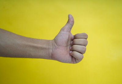 Close-up of human hand against yellow background