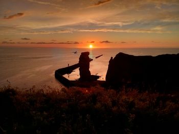 Silhouette man on beach against sky during sunset