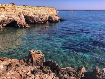 Rock formations by sea against sky