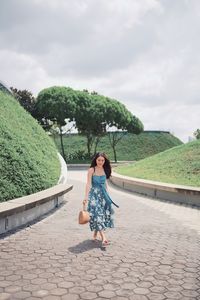 Full length of woman walking on footpath against sky