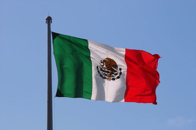 Mexican flag over blue sky in playa del carmen, mexico