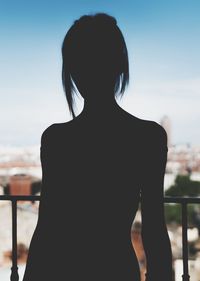 Rear view of silhouette woman standing against sky