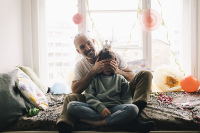 Portrait of happy man covering daughter's eyes during birthday celebration at home