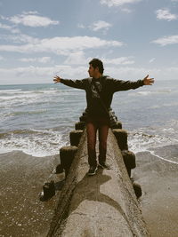 Full length of man with arms outstretched while standing on groyne