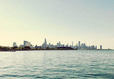 Sea by buildings against clear sky