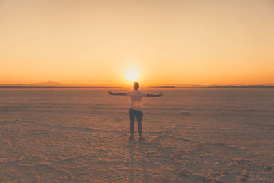 Silhouette man standing on beach at sunset