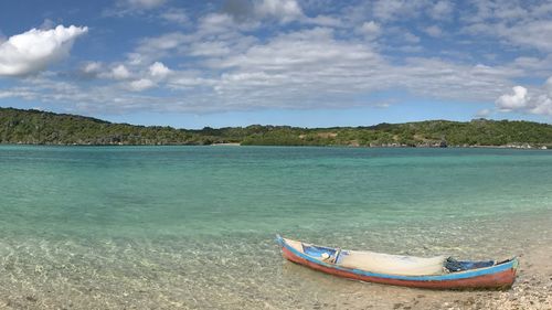 Boat moored on beach against sky