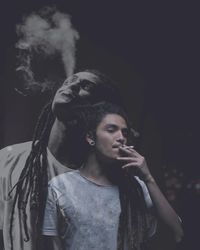 Double exposure image of young man smoking at night