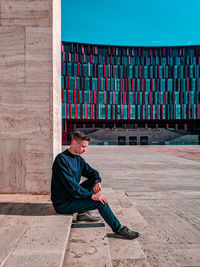 Full length of man sitting against wall