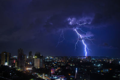 Lightning over illuminated buildings in city at night