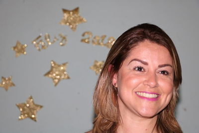 Close-up of woman smiling against golden star shapes on wall