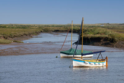 Sailboat moored on sea against clear sky