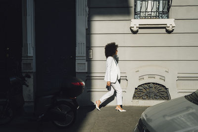 Young businesswoman walking by building