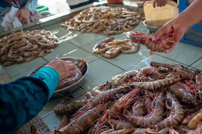 Cropped hands of people buying shrimps at market