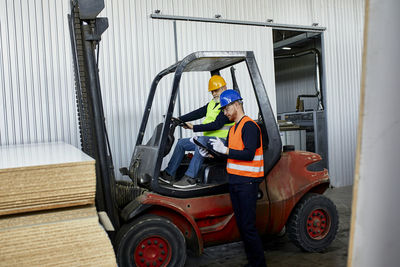 Man talking to worker on forklift in factory