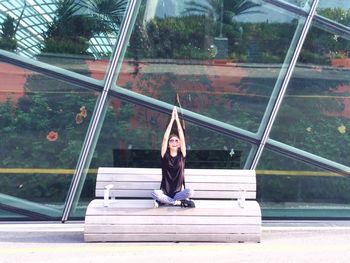 Full length of woman performing yoga against glass building