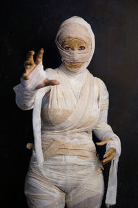 Portrait of woman in mummy costume during halloween standing against black background