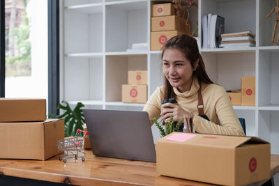 Portrait of young woman using mobile phone while sitting at home