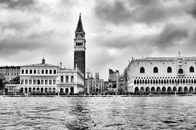 Grand canal by san marco campanile against cloudy sky