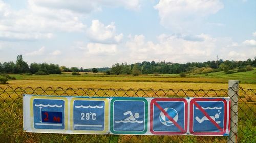 Information sign on field against sky