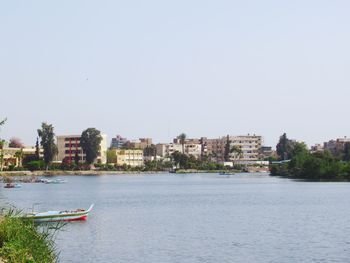 Scenic view of river by buildings against clear sky