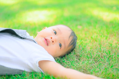 Portrait of cute boy lying on land