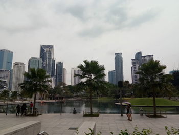 People in park against buildings in city against sky