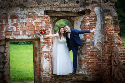 Bride and groom standing on abandoned wall