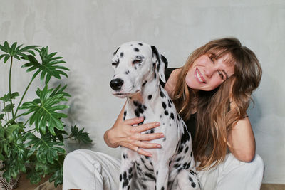 Portrait of woman with dog against wall