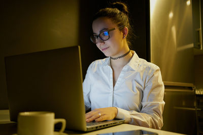 Young woman working with laptop in evening