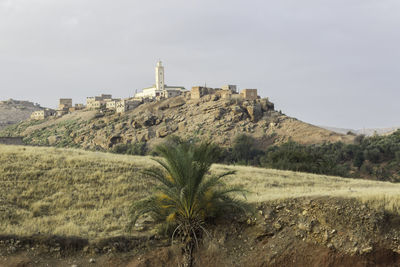 Lighthouse by mountain against sky