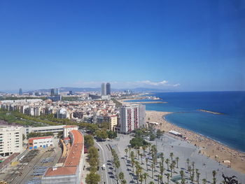 High angle view of buildings by sea against blue sky