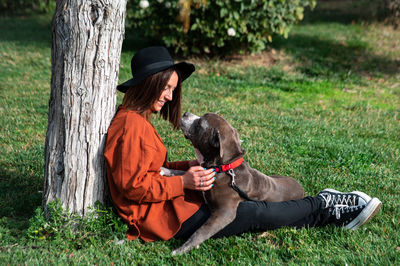 Woman sitting with dog in field