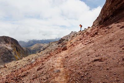 Man climbing on mountain against sky