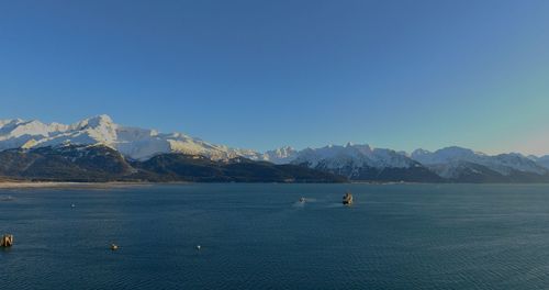 Scenic view of sea and mountains against clear blue sky