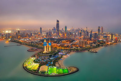 High angle view of illuminated city by river against sky